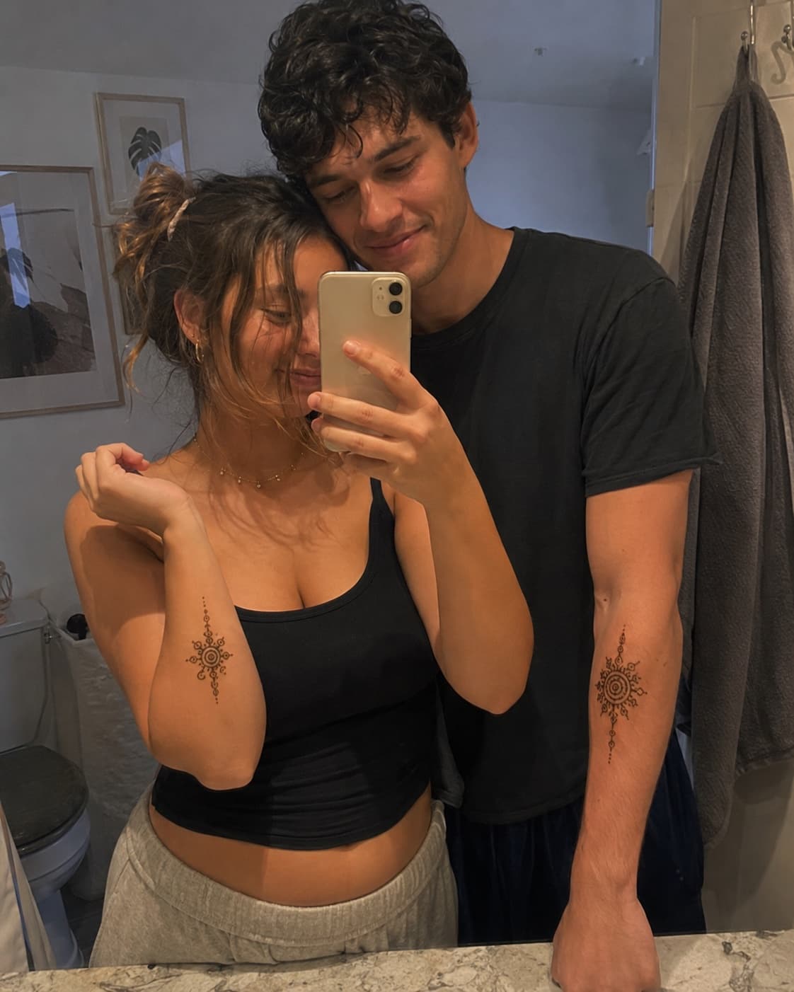 Mirror selfie of a couple showing off matching henna designs on their forearms